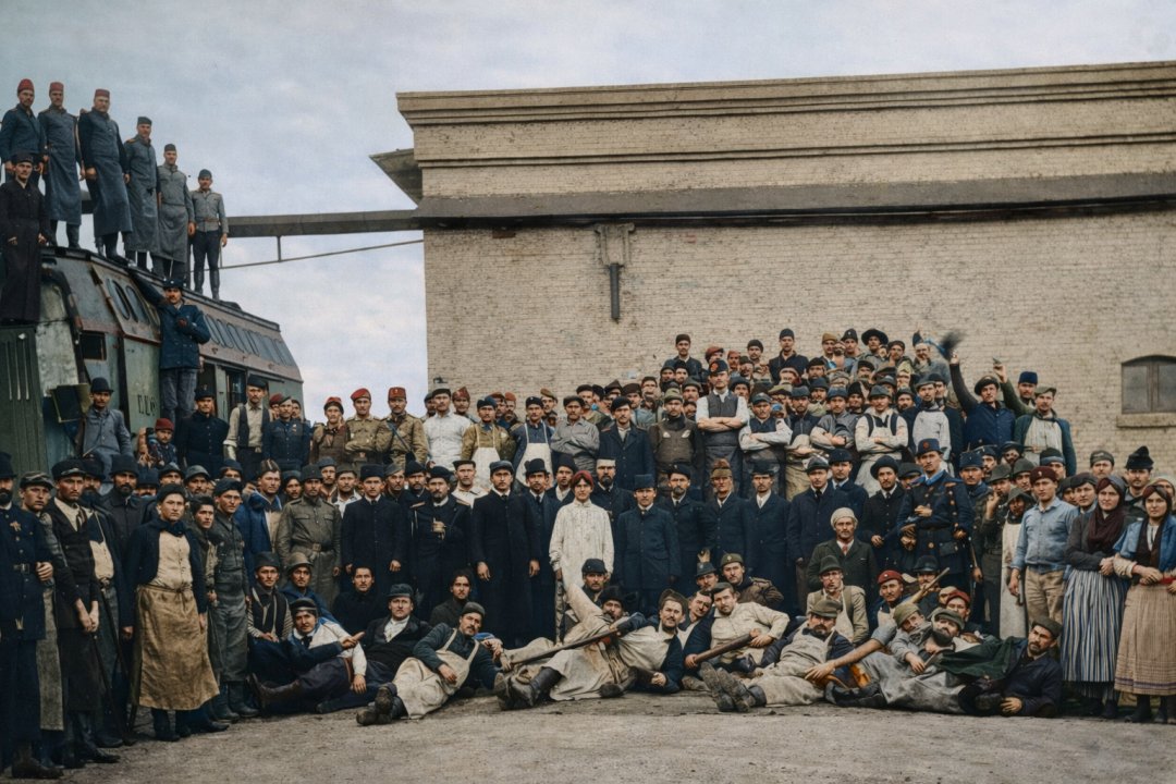 AI上色：贝尔格莱德牲畜屠宰加工股份公司（1906 年）。画面中，一米多长、比肌肉还粗的香肠，高举紧握的拳头和刀具，象征着团结的市民、屠夫、农民、卫兵、工人，背景中还有塞尔维亚国家铁路公司用于冰运肉类的专用车厢，展现了他们在关税战争期间争取经济独立的斗争。